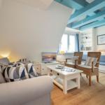 Wohnzimmer mit Sofa, Tisch und Stühlen unter blauen Balken.