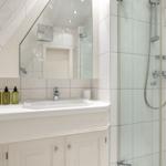 Badezimmer mit Dusche, Waschbecken und Spiegel
