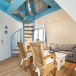Wohnbereich mit Sofa, Esstisch und blauer Wendeltreppe.