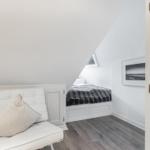 Bedroom with sloped ceiling, white bed, and gray floor