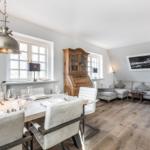 Dining area with table and chairs, living area with sofa and hardwood floor.