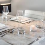 Table set with dishes, glasses, and candle for guests