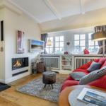 Wohnzimmer mit Kamin, rotem Sofa und Fenster mit Blick.