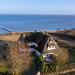 Dorfhaus mit Dach aus Gras, Blick auf Meer und Strand