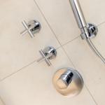 Duschkopf und Wasserhähne an Wand mit Chromfinish