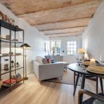 Living and dining area with wooden floor, table, and sofa under beam ceiling.