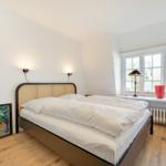 Bedroom with double bed, window, and wooden floor.