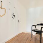 Room with wooden floor, black chair, and heart decor on the wall.