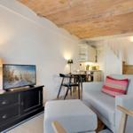 Living room with sofa, TV, and dining area under brick ceiling.