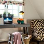 Schreibtisch mit Laptop, Stuhl und Blumen unter Fenster