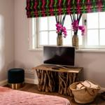 Ein Zimmer mit Bett, TV-Tisch aus Baumstämmen, Blumen und Fenster