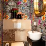 Badezimmer mit floraler Tapete, Waschbecken und Toilette.
