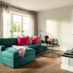 Ein Wohnzimmer mit grünem Sofa, Kamin und großem Fenster.