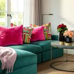 Ein grünes Sofa mit Kissen und einem Beistelltisch mit Blumen.