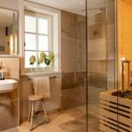 Badezimmer mit Dusche, Sauna und Waschbecken mit Spiegel.
