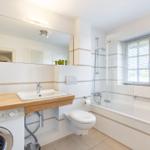 Badezimmer mit Dusche, Waschmaschine und Spiegel