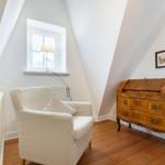 Dachzimmer mit Sessel, Holzschrank und Fenster
