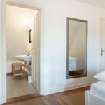 Schlafzimmer mit Spiegel und angrenzender Badewanne