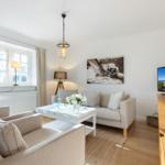 Wohnzimmer mit Sofa, Tisch und Fernseher an der Wand.