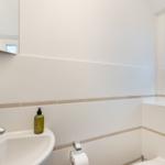 Badezimmer mit Waschbecken, Spiegel und Fenster