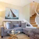 Wohnzimmer mit Sofa, Glas-Tisch und Treppe zur oberen Etage.