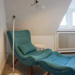 Blauer Sessel mit Fußstütze neben Bett und Fenster