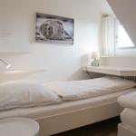 Zimmer mit zwei Betten, Wandbild und Fenster unter Dachschräge.