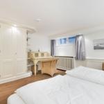 Schlafzimmer mit Bett, Schreibtisch und Kleiderschrank.