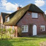 Red brick house with thatched roof and white door.