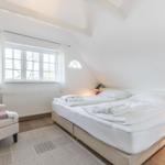 Bedroom with double bed, window, and seating area.