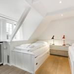 Room with two beds, windows, and wooden floor.