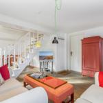 Living area with red cabinet, staircase, and sofa with cushions.