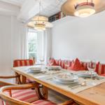Dining room with wooden table, striped cushions, and modern ceiling lights.