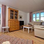 Wohnzimmer mit Holzfußboden, Sofa, Fernseher und Holzschrank.