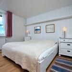 Schlafzimmer mit weißem Bett, Schrank und Fenster mit Blick auf den Himmel.