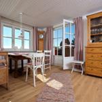 Esszimmer mit Holztisch, Stühlen und Schrank. Fenster und Tür zur Aussicht.