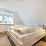 Bedroom with bed, window, and chair with lamp.