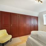 Bedroom with bed, yellow seating, and red wardrobe.
