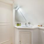 Bathroom with sink, mirror, and shower under sloped ceiling