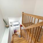 Wooden staircase with handrail and view into the lower room.