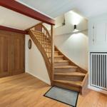 Wooden staircase leads to an upper level. Wooden floor, white walls, and wooden doors.