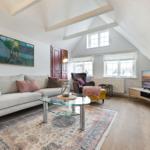 Living room with sofa, coffee table, and TV under wooden beam ceiling.