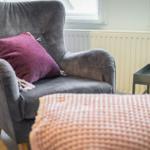 A gray armchair with a cushion and a side table.