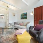 Living room with sofa, armchair, glass table, and rug.