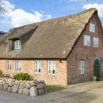 Traditional house with thatched roof and brick facade. Green door and windows.