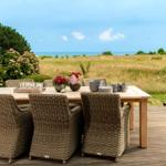 Terrasse mit Tisch und Stühlen, Blick auf das Meer und Grasland.