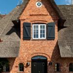 Rotes Backsteinhaus mit Strohdach und schwarzer Tür