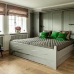 Schlafzimmer mit weißem Bett, grüner Sessel und Holzboden. An der Wand sind Schiebetüren.