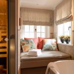 Dusche mit Sitzbank, Fenster und Sauna im Hintergrund.