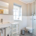 Bathroom with shower, sink, and toilet. Window with blinds.